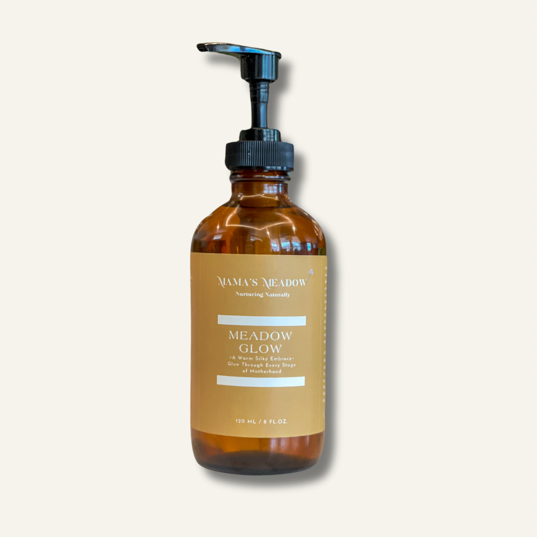 A clear glass bottle with a pump dispenser, labeled 'Meadow Glow - Body Oil'. The bottle is amber-colored and contains the product.